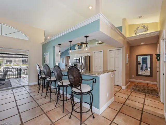 Kitchen with a kitchen breakfast bar, dark stone counters, appliances with stainless steel finishes, a high ceiling, and a peninsula