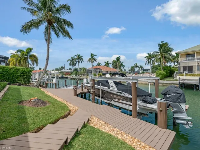 Dock featuring boat lift, a water view, and a yard