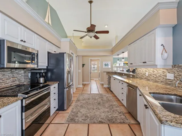 Kitchen featuring tasteful backsplash, appliances with stainless steel finishes, white cabinetry, and lofted ceiling