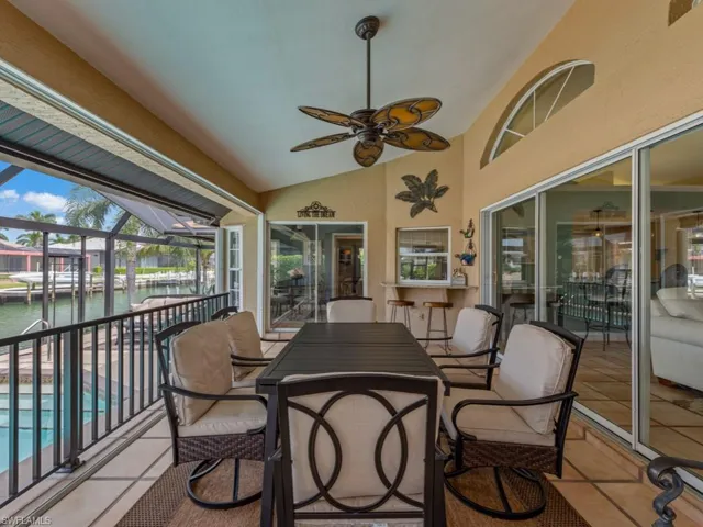 Sunroom featuring a water view, lofted ceiling, a patio area, outdoor dining area, and ceiling fan