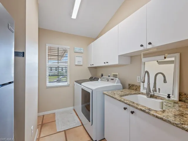 Laundry room with washer and dryer, light tile patterned floors, and cabinet space