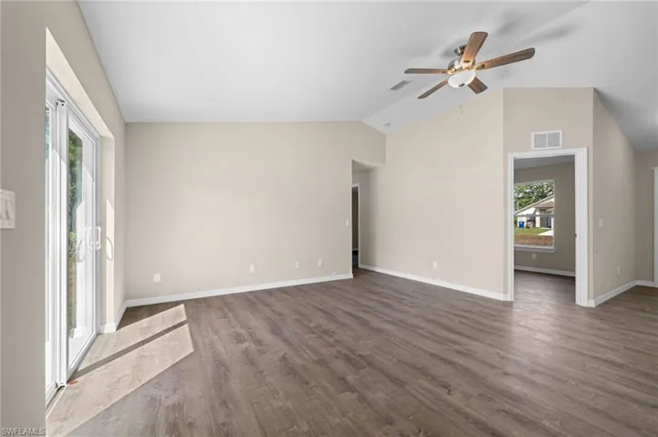 Unfurnished living room featuring dark hardwood / wood-style floors, plenty of natural light, and vaulted ceiling