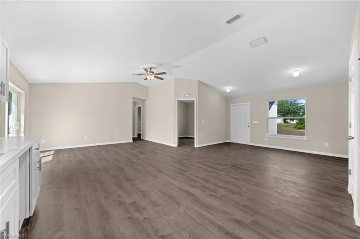 Unfurnished living room with ceiling fan, dark hardwood / wood-style flooring, and vaulted ceiling