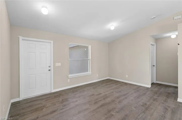 Spare room featuring hardwood / wood-style flooring and lofted ceiling