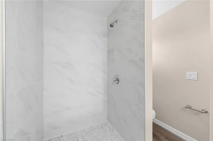 Bathroom featuring a tile shower and toilet