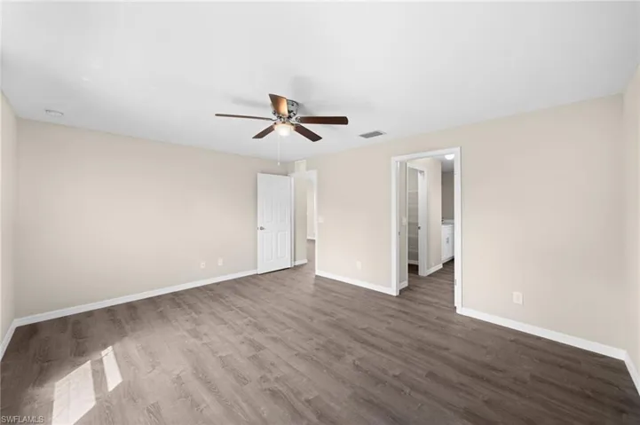 Empty room with dark hardwood / wood-style floors and ceiling fan