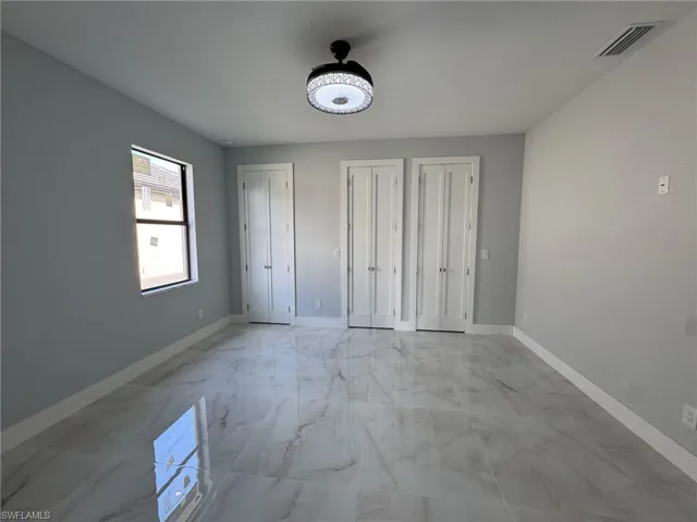 Unfurnished bedroom with multiple closets and light marble finish flooring