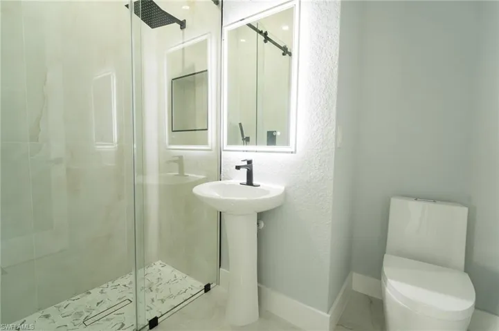 Bathroom with a stall shower, a textured wall, and tile patterned floors