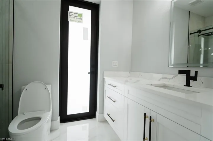 Full bath featuring a shower stall, vanity, and light marble finish flooring