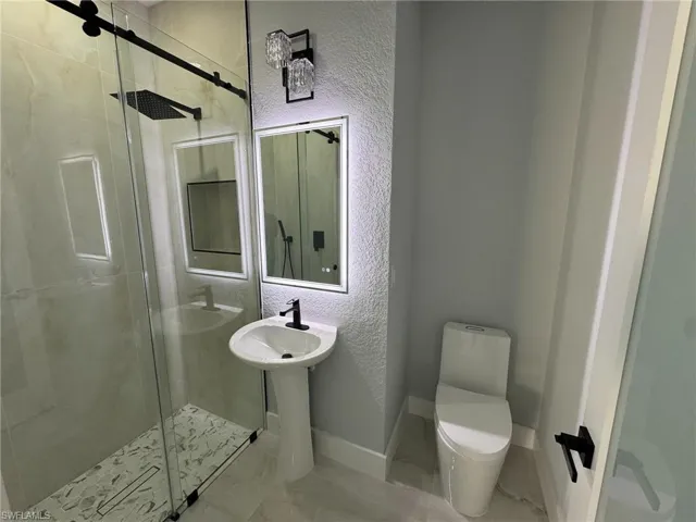 Full bathroom featuring a textured wall, a stall shower, and marble finish floors