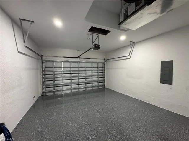 Garage featuring electric panel, a textured wall, and a garage door opener