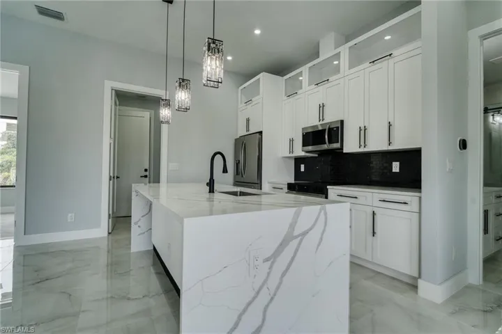 Kitchen with white cabinets, decorative light fixtures, light marble finish flooring, and recessed lighting