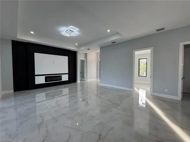 Spare room with light marble finish flooring, a raised ceiling, and recessed lighting