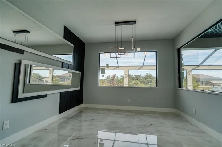 Unfurnished dining area featuring light marble finish floors, plenty of natural light, and a chandelier