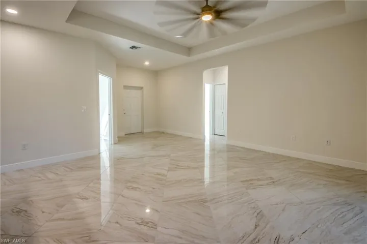 Spare room featuring a raised ceiling, recessed lighting, arched walkways, a ceiling fan, and light marble finish floors
