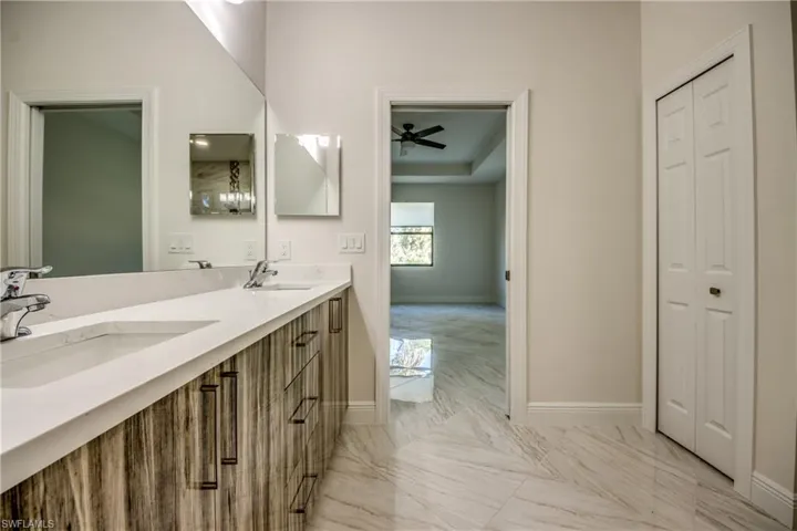 Bathroom with double vanity, light marble finish floors, and a ceiling fan