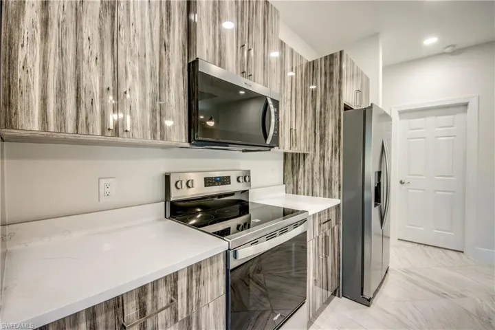 Kitchen with modern cabinets, stainless steel appliances, light stone counters, and recessed lighting