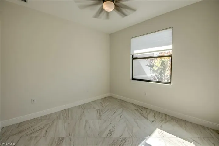 Unfurnished room featuring ceiling fan and light marble finish flooring