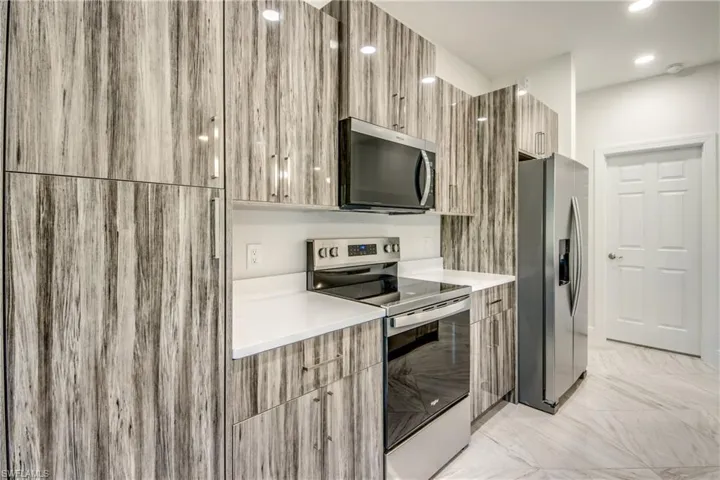Kitchen featuring modern cabinets, stainless steel appliances, and light stone counters