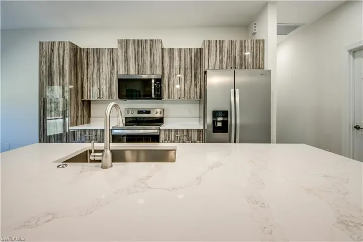 Kitchen with wood finish cabinetry, stainless steel appliances, light stone counters, and modern cabinets