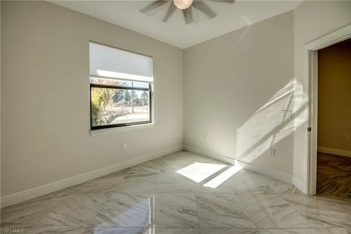 Empty room with ceiling fan and light marble finish floors