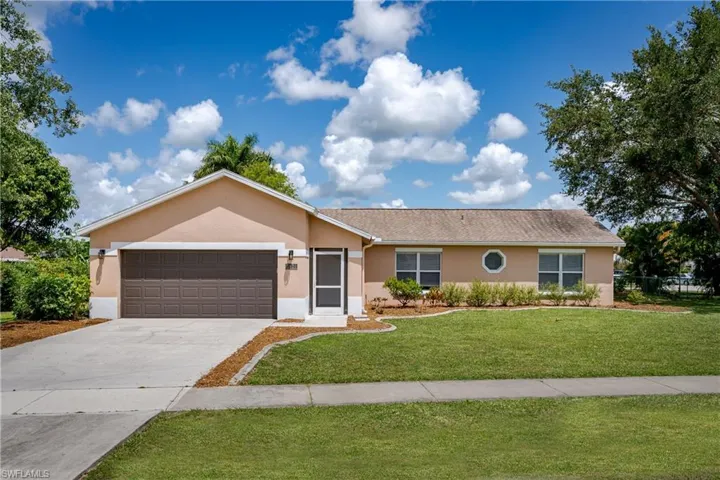 Single-story home featuring a two-car garage with a brown panel door, a screened entry, and a stucco exterior