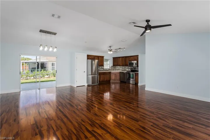 Open-concept living space featuring wood-finish flooring, a contemporary ceiling fan, and a kitchen with wood cabinetry and stainless steel appliances