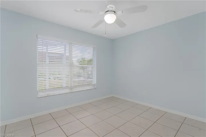 Light blue walls with a window featuring white blinds, complemented by a ceiling fan with integrated lighting