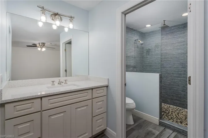Bathroom featuring a single vanity with light grey cabinetry, a light speckled countertop, and a rectangular undermount sink