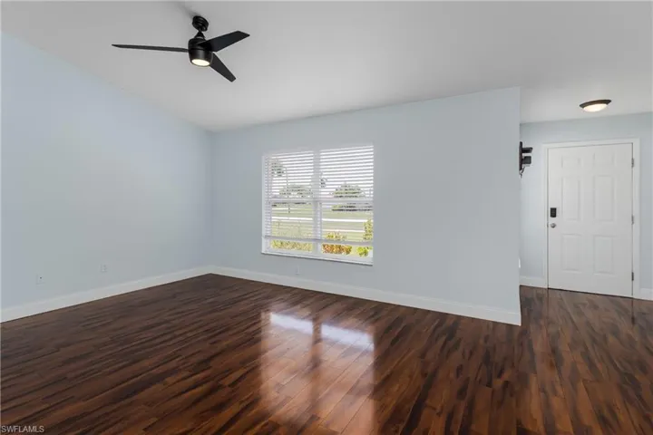 Bright living area featuring wood-finish flooring, light blue walls, and a contemporary ceiling fan with integrated lighting