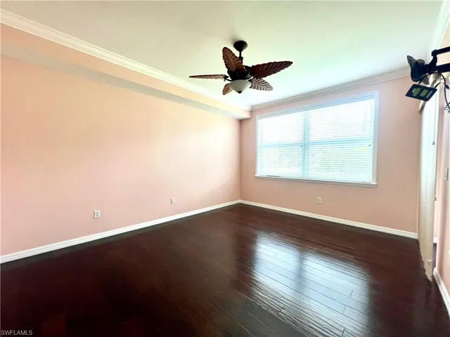 Unfurnished bedroom featuring ornamental molding, ceiling fan, and dark wood-style flooring