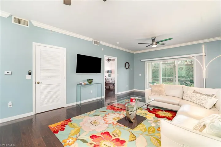 Living area with a ceiling fan, hardwood / wood-style floors, baseboards, and ornamental molding