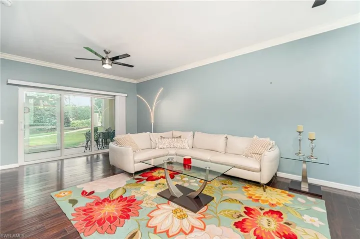 Living area with a ceiling fan, baseboards, hardwood / wood-style floors, and crown molding