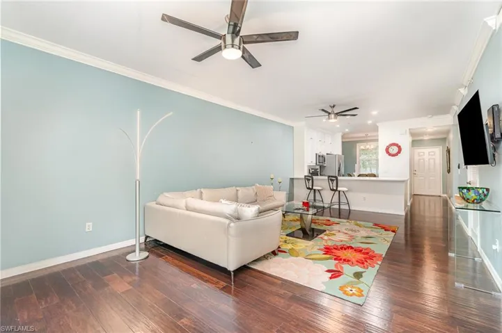 Living area with a ceiling fan, crown molding, baseboards, dark wood finished floors, and recessed lighting