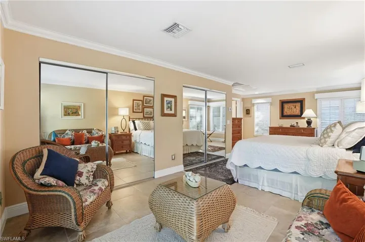 Bedroom with ornamental molding, multiple closets, and tile patterned floors