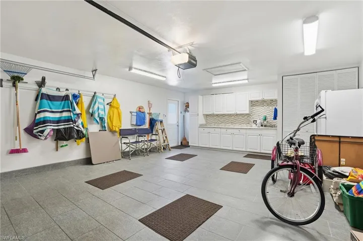 Spacious garage with cabinets, counter, and sink all under air with tile floors