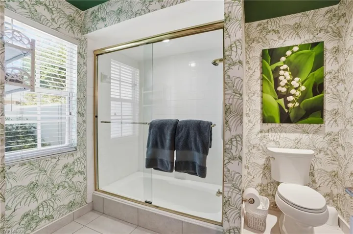 Natural light and festive wall paper make this spacious ensuite bathroom spa like