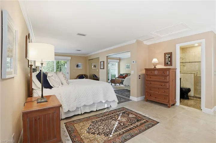 Bedroom with ornamental molding, attic access, two closets, and light tile patterned flooring