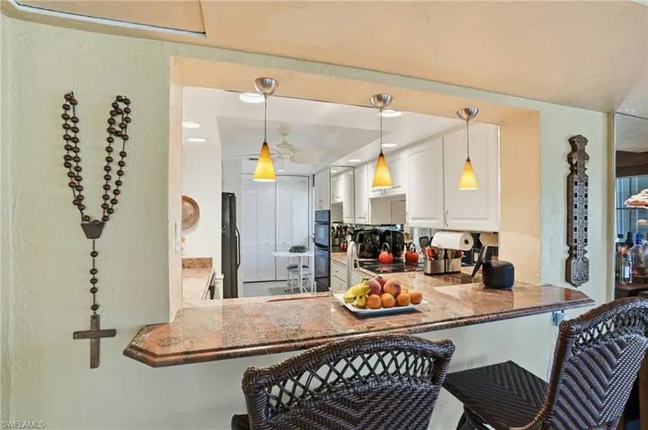 Kitchen featuring a breakfast bar, pendant lighting, white cabinets, black appliances, and recessed lighting