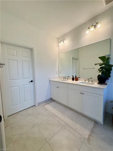 Full bathroom with double vanity, a sink, tile patterned floors, and a textured ceiling