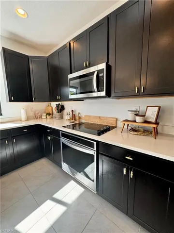 Kitchen with light countertops, dark cabinetry, stainless steel appliances, and light tile patterned flooring