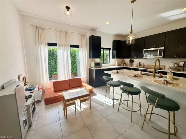 Kitchen featuring stainless steel microwave, light countertops, a breakfast bar area, and dark cabinets