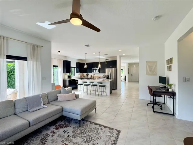 Living area with light tile patterned floors, baseboards, visible vents, ceiling fan, and recessed lighting