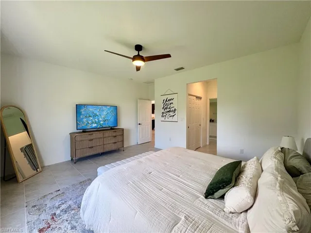 Bedroom with visible vents, a ceiling fan, and light tile patterned floors