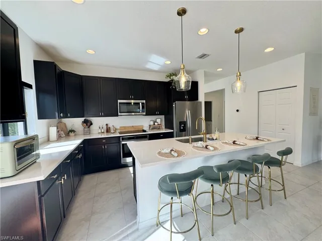 Kitchen featuring light countertops, a sink, stainless steel appliances, and dark cabinetry