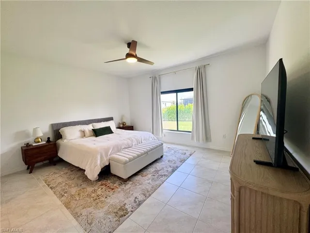 Bedroom with a ceiling fan, light tile patterned flooring, and baseboards