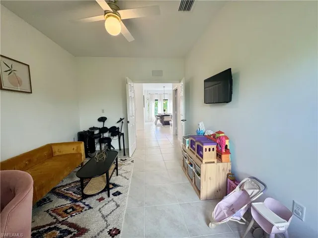Living room featuring light tile patterned flooring, visible vents, and ceiling fan