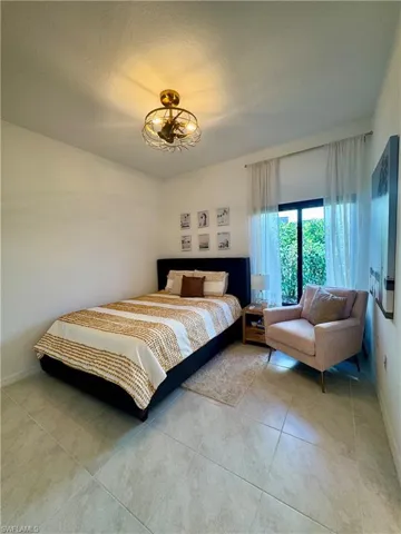Bedroom with a textured ceiling, baseboards, and light tile patterned floors