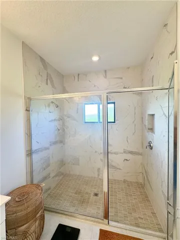 Bathroom featuring a marble finish shower and a textured ceiling