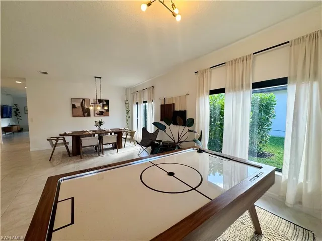 Playroom with light tile patterned flooring, visible vents, and a notable chandelier
